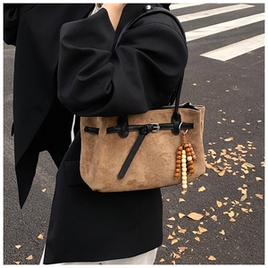 Borsa tote in camoscio marrone con perle di legno in un elegante contesto urbano autunnale
