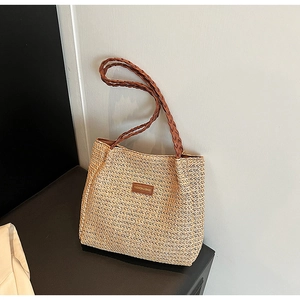 Close-up of woven straw tote bag featuring contrast stripes and leather logo patch