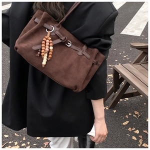 Borsa tote in pelle scamosciata marrone con nappe di legno portata a spalla in città