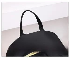 Gros plan sur la poignée supérieure en nylon noir et le zip métallique d'un sac à dos chic