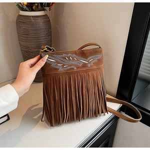 Detail of bohemian brown suede crossbody bag with ethnic embroidery and long tassels