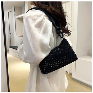 Close-up of black rhinestone baguette bag with stylish knotted strap detail on shoulder