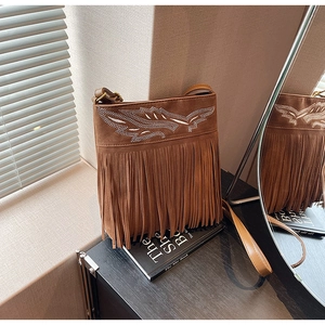 Detailed macro view of bohemian brown suede crossbody bag with fringe and wing embroidery