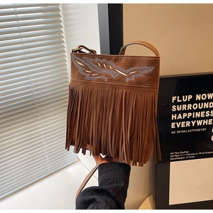 Detail view of brown suede crossbody bag featuring silver rhinestone leaf and long fringes
