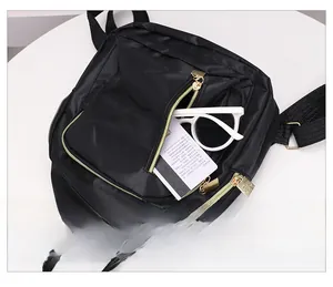 Détail de la poche zippée avant sur sac à dos noir en nylon avec finitions dorées