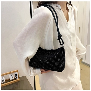 Detail of black rhinestone hobo bag with knotted shoulder strap worn on a white shirt
