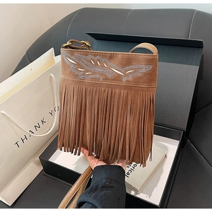 Detail view of ethnic brown suede bag featuring feather embroidery and long tassel fringe