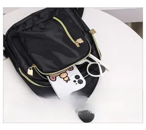 Détail de la poche avant du sac à dos en nylon noir avec fermeture éclair dorée et objets