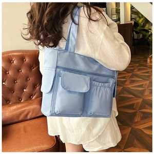 Detail view of light blue tote bag with multiple pockets and waterproof nylon fabric