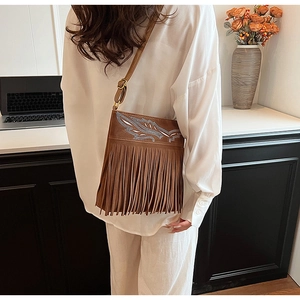 Close-up of ethnic brown shoulder bag with feather embroidery and long tassel details