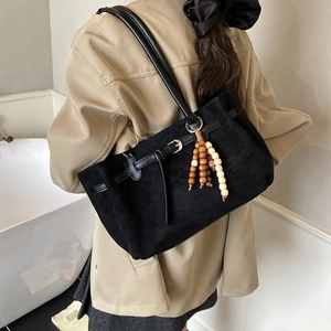 Borsa tote vintage in pelle scamosciata nera con nappina indossata in una stanza sobria