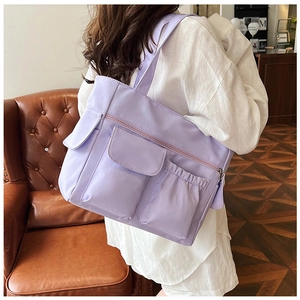 Detail of light purple nylon tote bag with three functional pockets shown on shoulder
