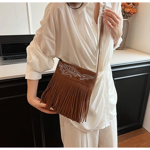 Close-up of brown suede shoulder bag with long fringes and embroidered sequins pattern