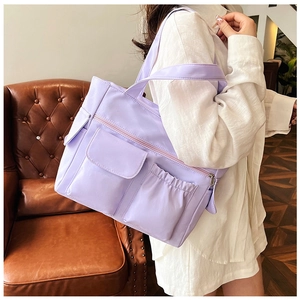 Detailed lifestyle view of a lavender nylon tote bag with functional pockets and shoulder strap