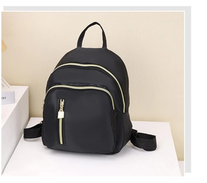 Vue détaillée du mini sac à dos noir en nylon avec fermetures éclair dorées et poches