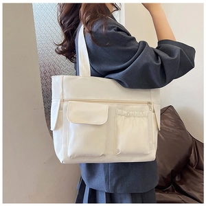 Detail of the multi-pocket cream tote bag showing its side storage and wide shoulder strap