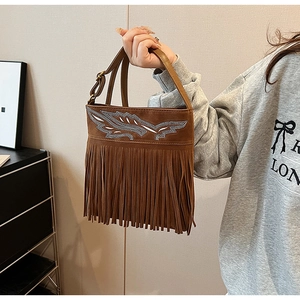 Detail of bohemian brown suede bag with silver rhinestone feather and fringe