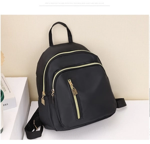 Détail d'un mini sac à dos noir en nylon avec fermetures dorées et bretelles tissées
