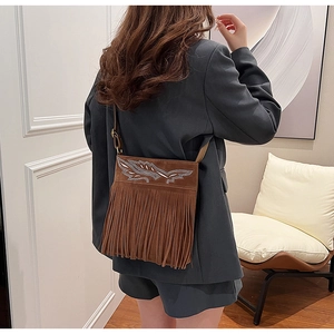 Close-up of brown suede crossbody bag with ethnic embroidery and long fringe tassels