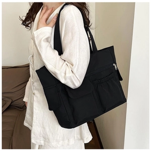 Detailed view of black multi-pocket tote bag with front flap pockets and side storage