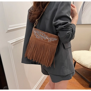 Detail view of ethnic suede shoulder bag featuring sparkling wing embroidery and long fringes
