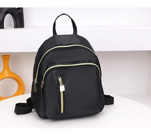 Détail d'un mini sac à dos noir en nylon avec fermetures éclair dorées chic