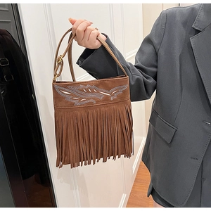 Close-up of brown fringe shoulder bag with silver wing embroidery and bohemian style