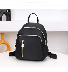 Vue détaillée d'un mini sac à dos en nylon noir avec plusieurs poches et fermetures dorées