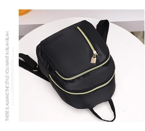 Vue détaillée du sac à dos en nylon noir avec fermetures dorées et pendentif en métal