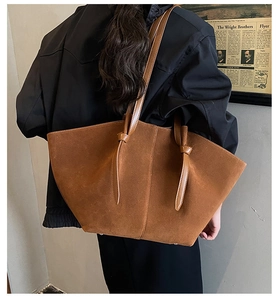 Detail of brown suede tote bag featuring knotted shoulder straps and large capacity