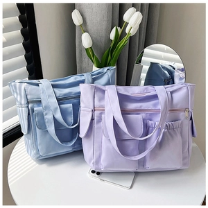 Close-up of functional multi-pocket tote bags in soft blue and purple nylon fabric