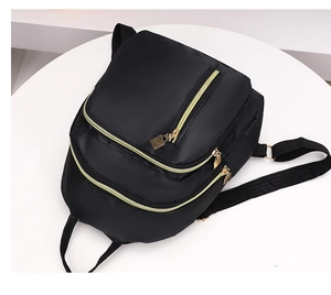 Gros plan détaillé d'un sac à dos en nylon noir avec fermetures éclair dorées chic