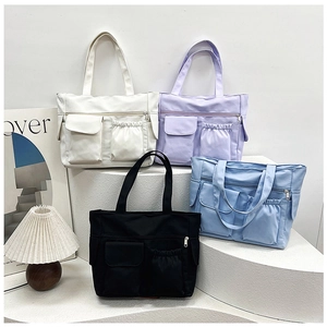 Detail view of multi-pocket nylon tote bags in white, lavender, light blue, and black