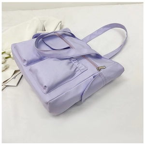 Detail view of a lilac canvas tote bag featuring multiple pockets and silver metal zippers