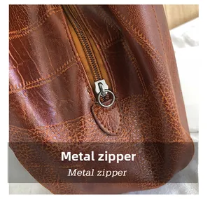 Close-up of metal zipper and textured dark brown vintage leather on a tote bag