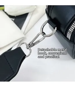 Détail du crochet en métal argenté et de la bandoulière amovible du sac en cuir noir