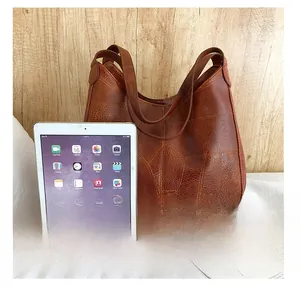 Detail of vintage brown leather tote bag showing patchwork seams next to an iPad for size comparison