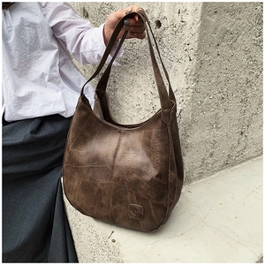 Detail of vintage brown textured leather hobo bag with embossed logo and long straps