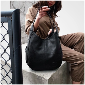 Detail of black large capacity hobo bag featuring geometric stitching and embossed logo
