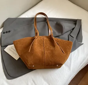 Detailed view of the brown suede tote bag with metal studs and slender leather straps