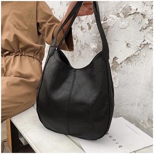 Detail of black pebbled leather tote bag featuring geometric stitching and hobo style shape