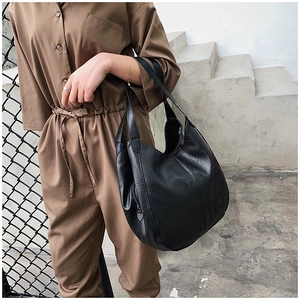 Detail shot of black pebbled leather tote bag with functional side zipper on model