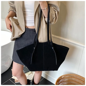 Detail of a black leather tote bag with wing design and slender shoulder straps