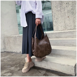 Detail of a large vintage dark brown hobo tote bag with soft leather texture on a shoulder