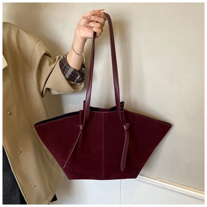 Detail of dark wine red suede tote bag held by a model in a trench coat