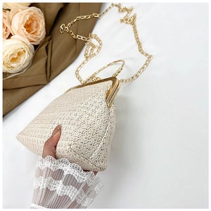 Detailed macro view of woven straw clutch with gold metal frame and handle