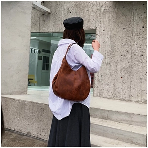 Detailed back view of a vintage tan leather tote bag showing unique asymmetric stitching