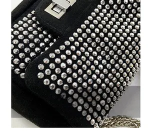 Dettaglio ravvicinato di una borsa in camoscio nero con strass d'argento e catena
