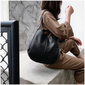 Detail of black pebbled leather hobo bag showing texture and embossed patch logo