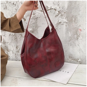 Detail shot of vintage dark red tote bag with soft oily leather texture and square logo
